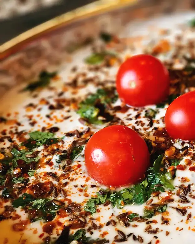 Creamy curd topped with cherry tomatoes, herbs and chilli flakes