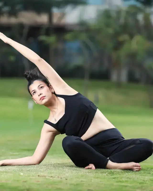 A woman stretching in a yoga pose on a lawn