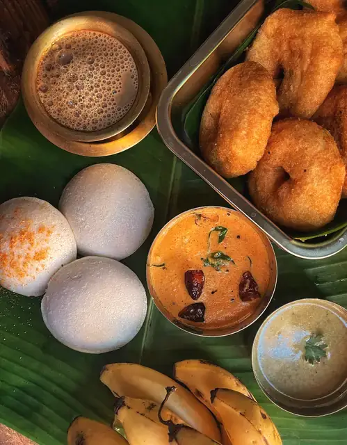 Idli, medu vada, sambar and filter coffee on a banana leaf